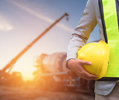 Engineer or Safety officer holding hard hat with the mobile crane machine is background in construction site.