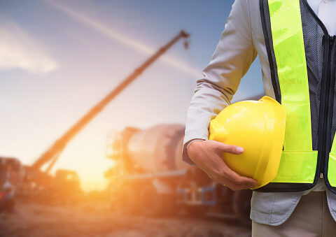 Engineer or Safety officer holding hard hat with the mobile crane machine is background in construction site.