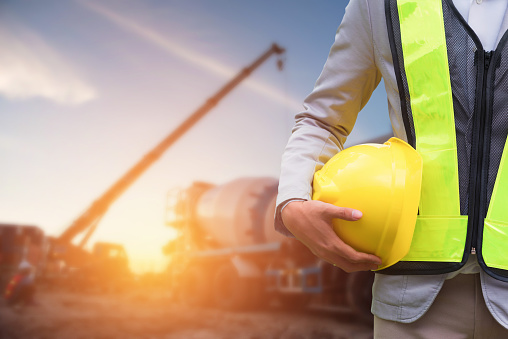 Engineer or Safety officer holding hard hat with the mobile crane machine is background in construction site.